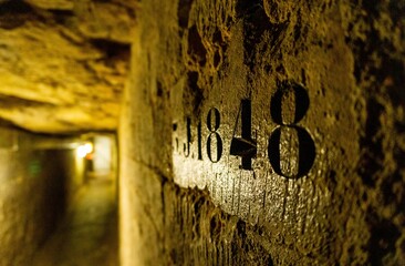 Numbers engraved on the wall of the catacombs of Paris in focus, with the background out of focus