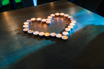 Heart from burning candles close-up on a wooden table.
