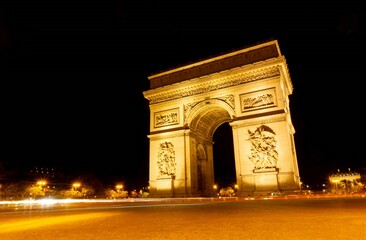 Fototapeta na wymiar The Arc de Triomphe illuminated on a dark night, with the lights of the cars photographed by a long exposure