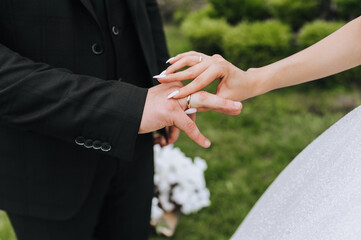 The bride at the ceremony puts a gold ring on the groom's hand, finger. Wedding photography, concept.