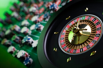 
Casino. Gambling games theme.  Roulette wheel, dice and poker chips on the casino felt green table.
