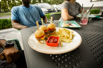 Mini burgers on white plate on black cafe table