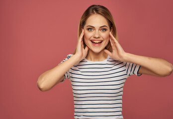 blonde woman in a striped T-shirt fun hand gestures pink background