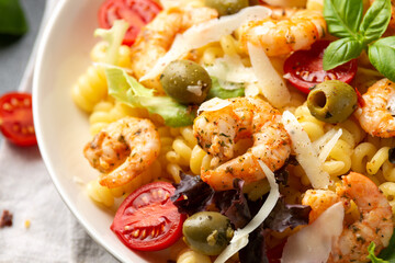 King prawn pasta salad with marinated green olives, cherry tomatoes and parmesan cheese shavings. Healthy food.