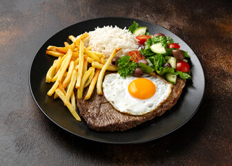 Portugal dish Bitoque made from beef steak with a fried egg, rice, french fries and vegetables