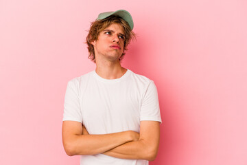 Young caucasian man with make up isolated on pink background tired of a repetitive task.
