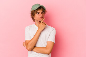 Young caucasian man with make up isolated on pink background contemplating, planning a strategy,...