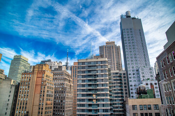 Modern and old buildings and skyscrapers of Midtown Manhattan under a blue sky, New York City - NY...