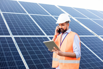 The young electrician works at a solar station using gadgets