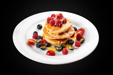 Pancakes with caramel and seasonal berries on a blacktop. Breakfast