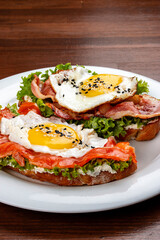 Toast with salmon, bacon and cream cheese.  On a wooden background. Breakfast