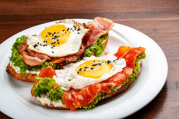Toast with salmon, bacon and cream cheese.  On a wooden background. Breakfast