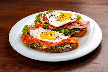 Toast with salmon, bacon and cream cheese.  On a wooden background. Breakfast