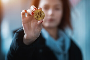 closeup of female investor holding golden bitcoin or cryptocurrency in hand