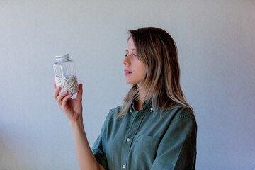 woman holding a transparent jar with white pills