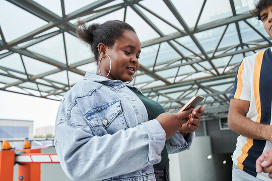 Multiracial woman using her smartphone while standing near her best friends - Powered by Adobe