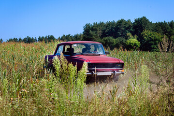 Old Soviet car drives off-road in a field