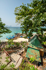 Naklejka premium Stairs going down to a beach with long tail boats on Phi Phi island next to a bungalow with green roofs
