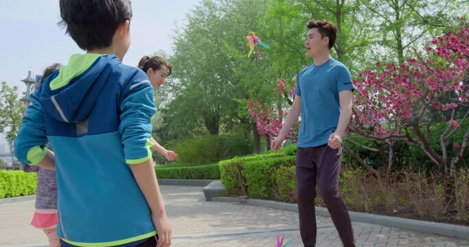 Happy young family kicking shuttlecock in park,4K
