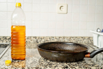 Plastic bottle with recycled edible oil next to frying pan in the kitchen of a house. Recycling concept in the home. High quality photo