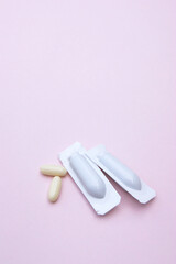 Gynecological medicines for women's health in form of suppository, capsules on pink background.