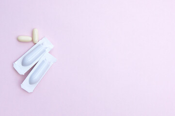 Gynecological medicines for women's health in form of suppository, capsules on pink background.
