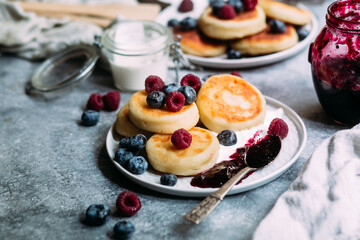 cheesecakes with berries and sauce on a gray background