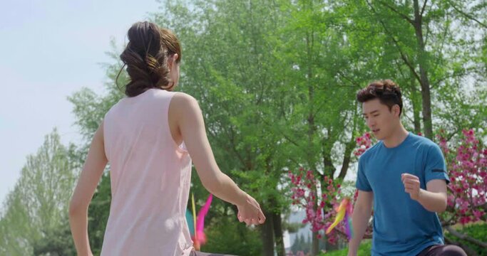 Happy young couple kicking shuttlecock in park,4K