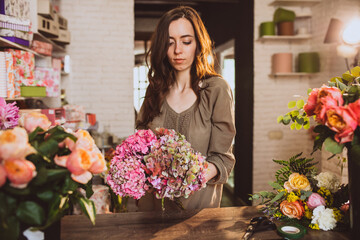 Fototapeta premium Woman florist at her own floral shop taking care of flowers