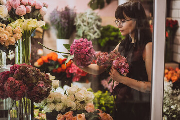 Woman florist at her own floral shop taking care of flowers