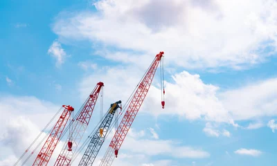Fotobehang Crawler crane against blue sky and white clouds. Real estate industry. Red crawler crane use reel lift up equipment in construction site. Crane for rent. Crane dealership for construction business. © Artinun