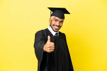 Young university graduate Colombian man isolated on yellow background with thumbs up because something good has happened