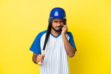 Young Colombian latin man playing baseball isolated on yellow background frustrated and covering ears