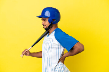 Young Colombian latin man playing baseball isolated on yellow background suffering from backache for having made an effort