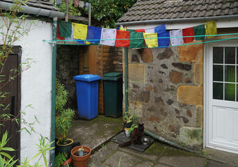 Fototapeta na wymiar Tibetan prayer flags in the backyard and a black cat, Oban, Scotland