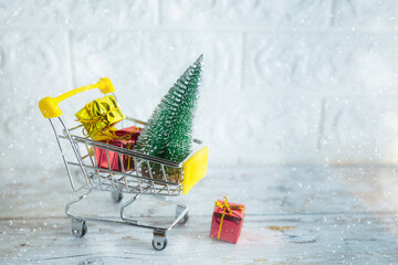 Christmas shopping season concept - mini shop cart trolley full of gift box on white brick...