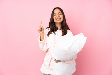 Young woman in pajamas isolated on pink background showing and lifting a finger in sign of the best