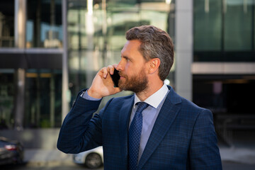 Businessman talking on phone. Portrait of cheerful Business man office worker talking on mobile phone while standing near modern office.