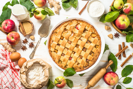 Apple pie. Traditional apple cake with ingredients for cooking at white wooden table. Top view image.