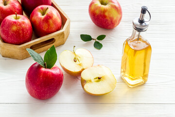 Apple cider vinegar in glass bottle with fresh red apples