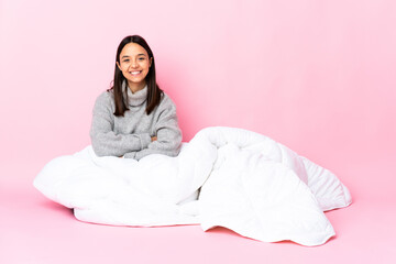 Young mixed race woman wearing pijama sitting on the floor keeping the arms crossed in frontal position