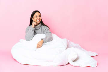 Young mixed race woman wearing pijama sitting on the floor laughing