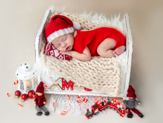 Newborn in santa suit resting on bed