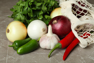 String bag with spicy vegetables and parsley on gray textured background