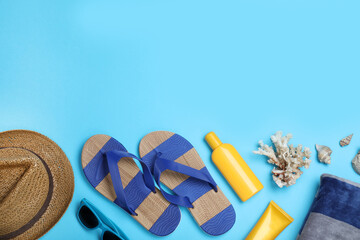 Stylish flip flops and beach objects on light blue background, flat lay. Space for text