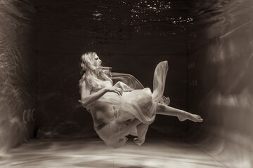 A girl with long hair swims underwater in a pink dress. She looks like an underwater dragon. Suitable for advertising