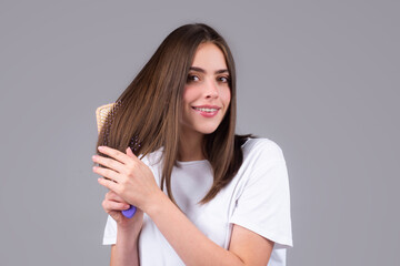 Portrait of charming brunette hair lady combing hair with hairbrush comb, isolated. Young beautiful woman brush long healthy brunette hair, classic hairstyle, restoration mask, haircare concept.