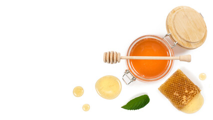 Glass of the honey, piece of bee comb, honey dipper and mint leaf on white background. View from above.