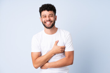 Young Moroccan man isolated on blue background smiling a lot