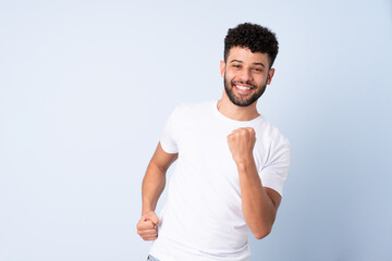 Young Moroccan man isolated on blue background celebrating a victory